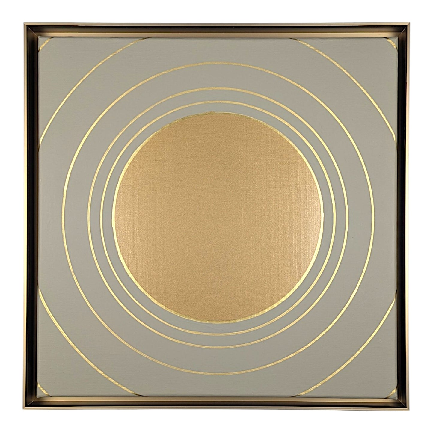 Square decorative wall art featuring a metallic gold circular motif surrounded by concentric gold rings on a light gray background, enclosed in a thin gold-toned frame.