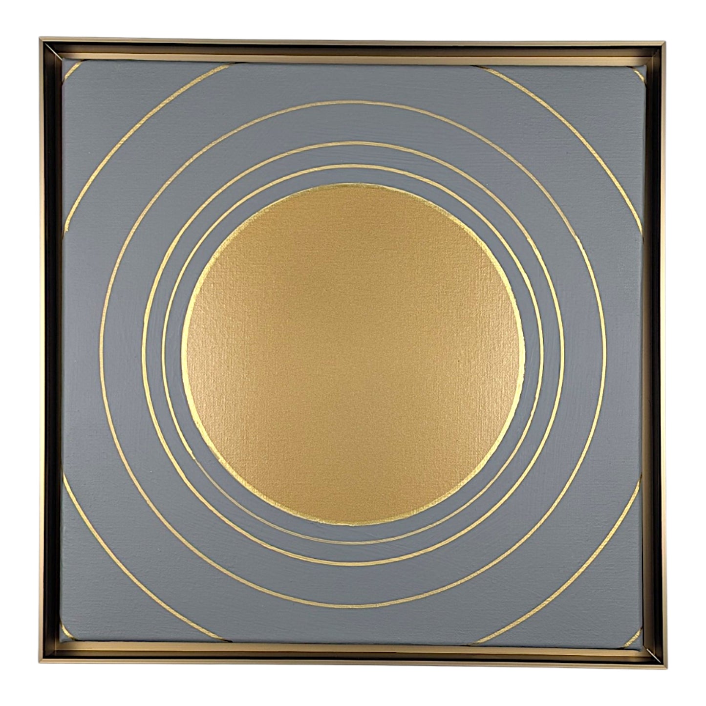 Square framed wall art featuring a metallic gold sun-like circle centered on a slate gray background with concentric gold rings and a thin gold frame.