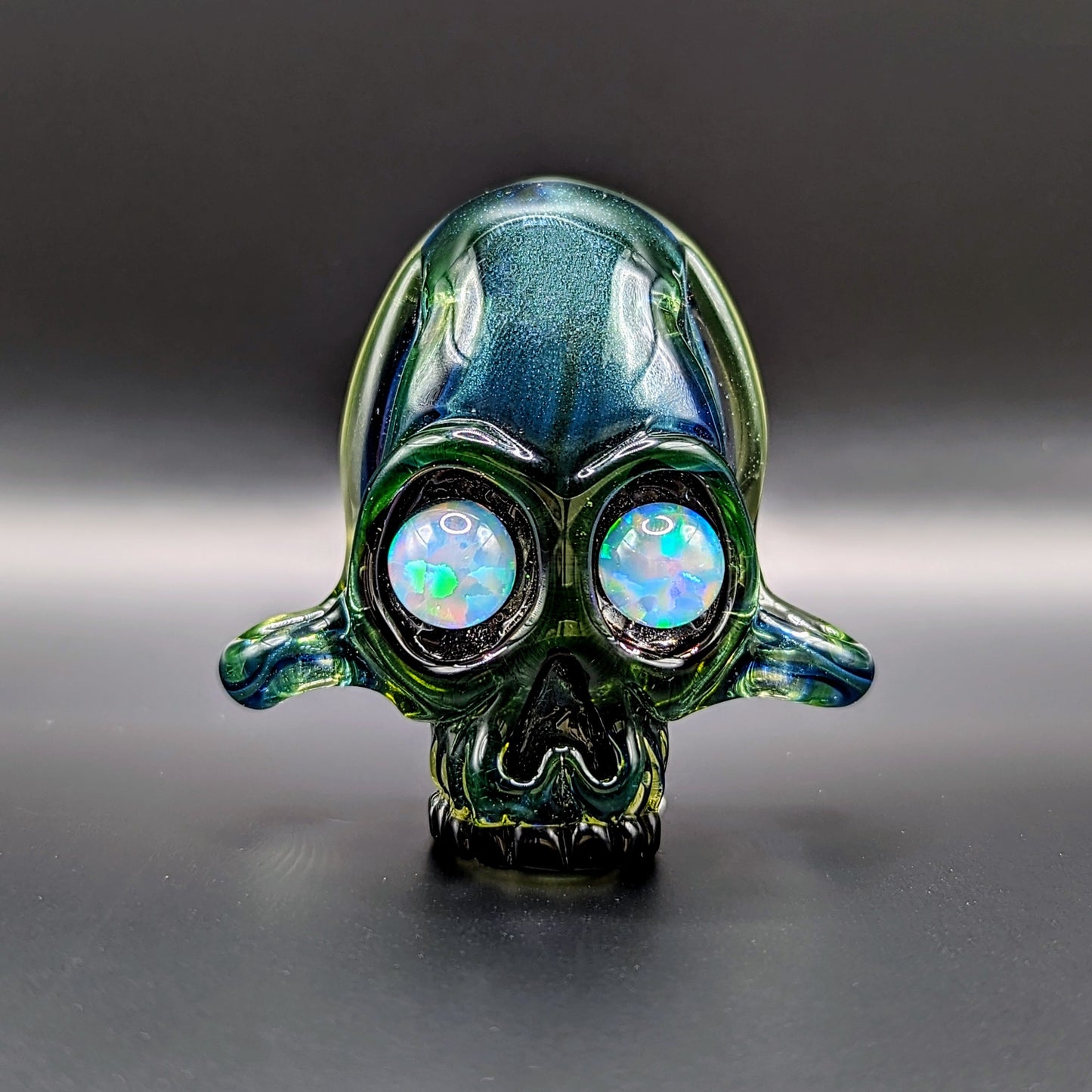 AKM  Skull, 2015 Illuminati Sleeved Borosilicate Glass Pendant with Opal Eyes Approx. 2.4 x 2.4 in  Hand blown glass made by AKM. Signed "AKM" + Dated "2015"