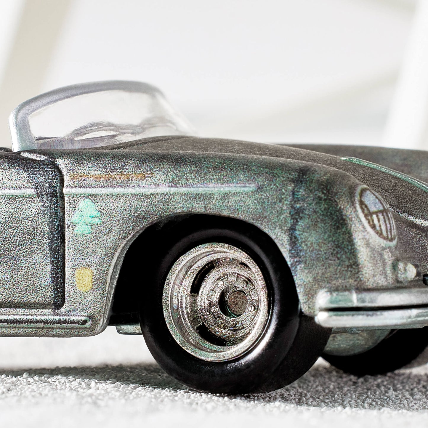 Daniel Arsham x Hot Wheels Porsche 356 “Bonsai” Speedster, 2023 Features: Sculpted crystallized erosions Body Color: Weathering effect to match ZAMAC color Body Type: ZAMAC Chassis: ZAMAC Wheels: Real Riders deep dish wheels with wash/wipe weathering effect Window Color: Clear Interior Color: Plastic replica of 1:1 version’s indigo-dyed Japanese textiles Scale 1:64 Includes sealing label and Certificate of Authenticity Packaged in a collector display case with simulated concrete base.