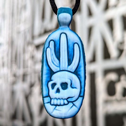 Kellie Thurston Skull & Cactus (Aqua Azul under Lotus White), 2024 Borosilicate Glass Pendant 60 mm x 24 mm  Hand carved borosilicate glass pendant by Kellie Thurston. Prep by Dan Longden. 