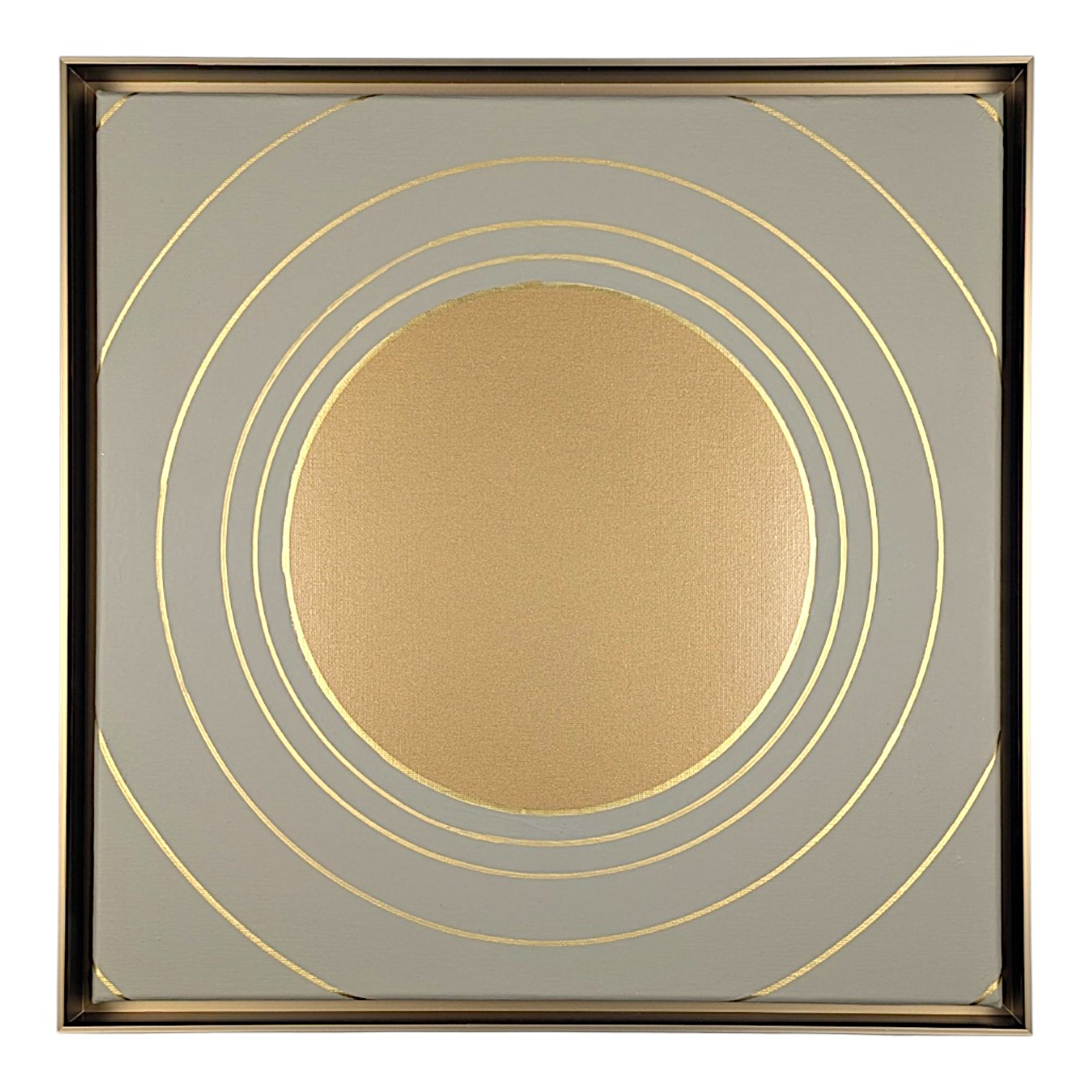Square decorative wall art featuring a metallic gold circular motif surrounded by concentric gold rings on a light gray background, enclosed in a thin gold-toned frame.