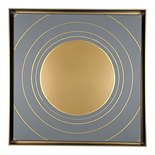 Square framed wall art featuring a metallic gold sun-like circle centered on a slate gray background with concentric gold rings and a thin gold frame.